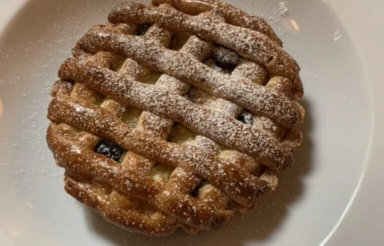 Ricotta and sour cherry tart, baked golden brown with lattice shortcrust top and dusted with icing sugar
