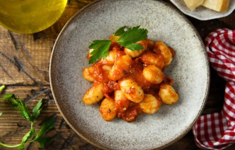 Gnocchi with tomato ad chicken sauce on a wood table with checked table cloth